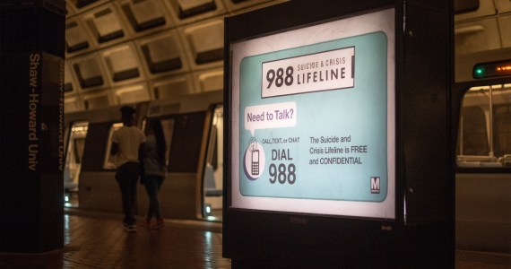 A photo of an advertisement inside of a subway station that reads, "988 Suicide & Crisis Lifeline. Need to talk? The Suicide and Crisis Lifeline is free and confidential."