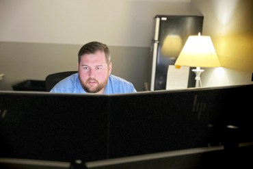 A photo of a man working on a computer at his desk.