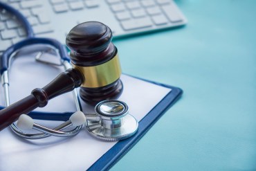 a gavel and stethoscope set on a blue table beside a computer keyboard