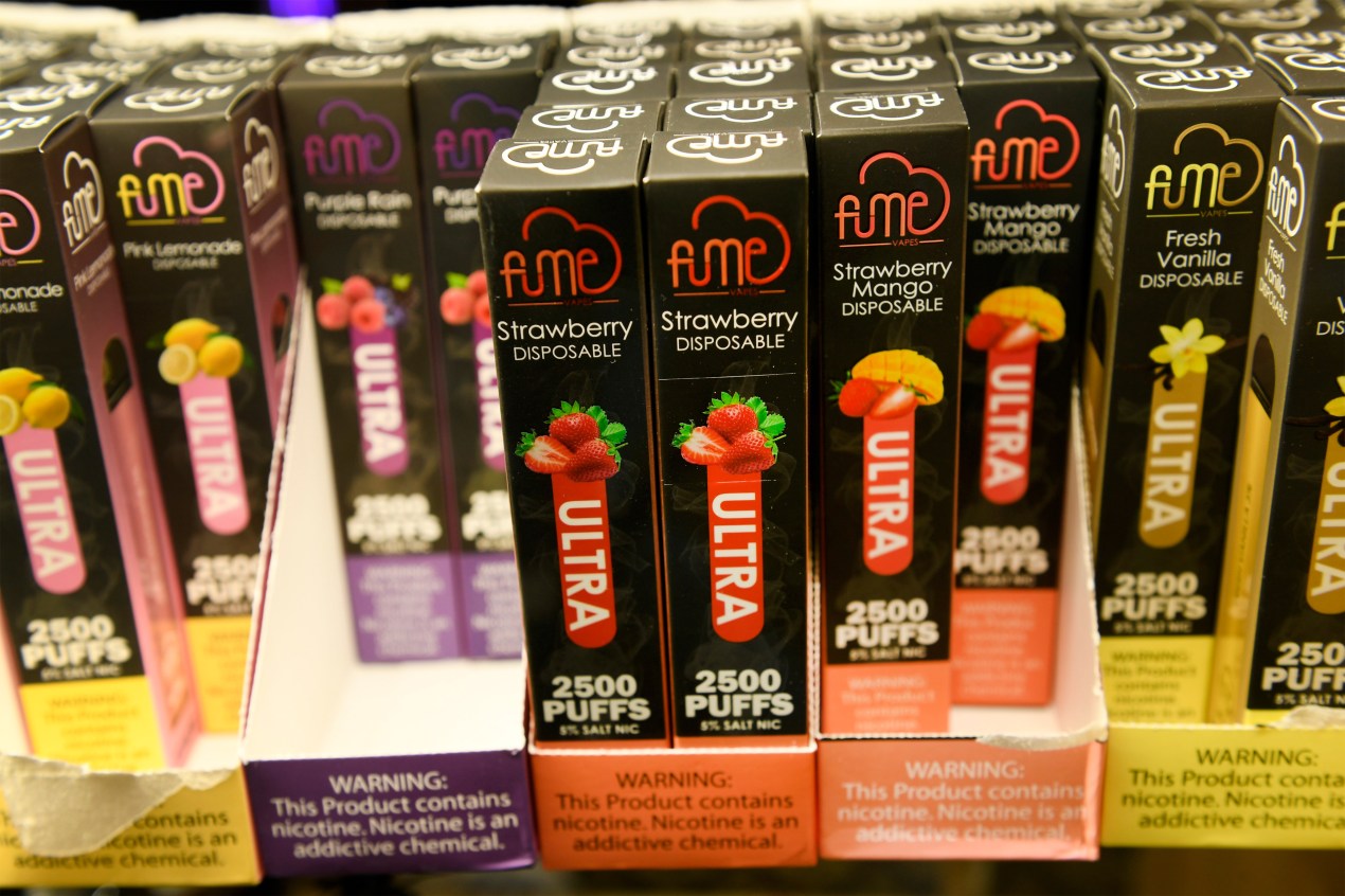 A photo of various flavored e-cigarette products on a store shelf.