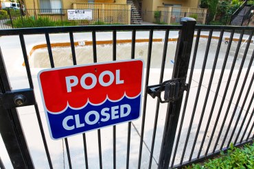 A photo of a gate with a sign that reads, "Pool closed."