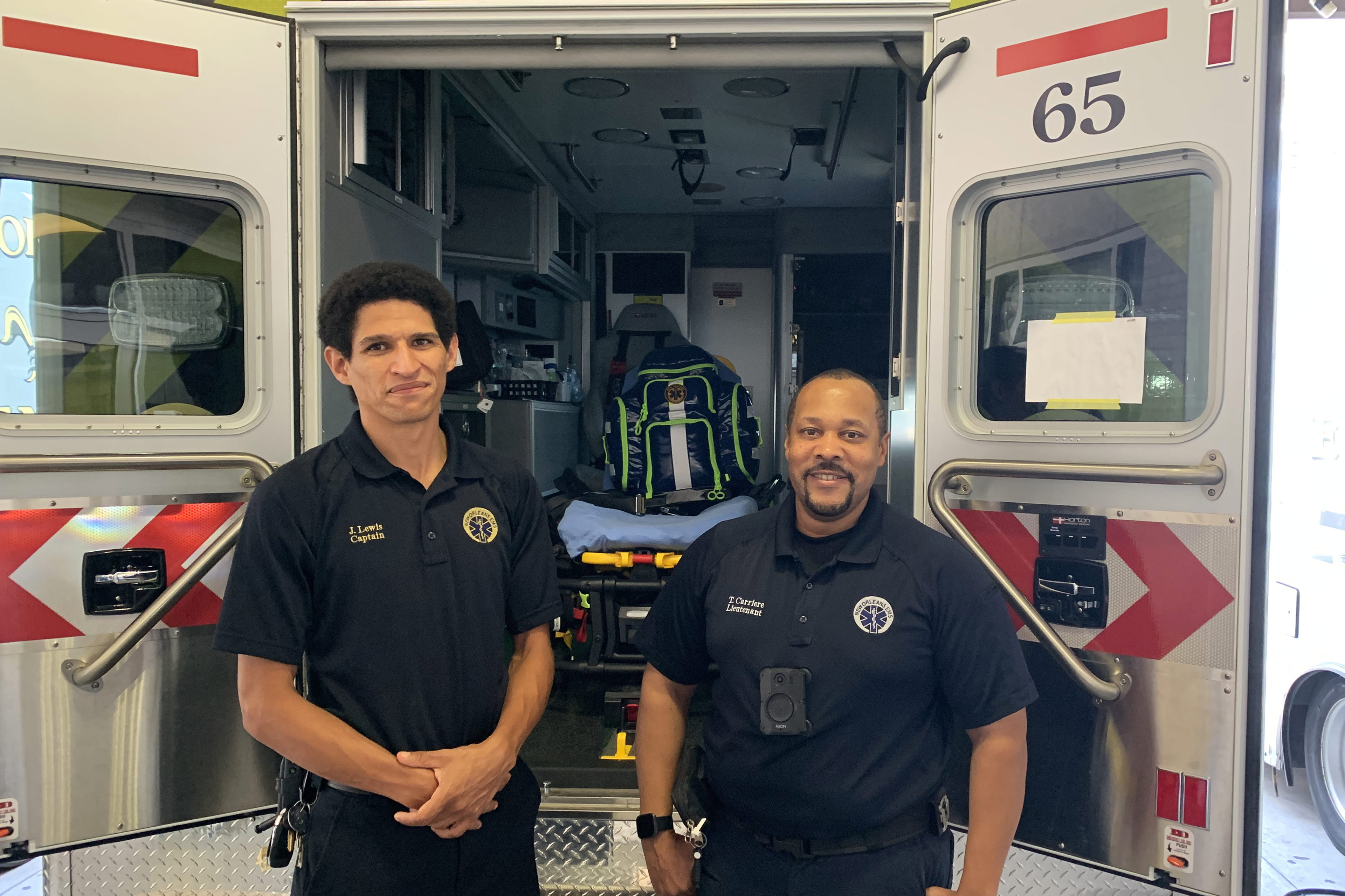 A photo of two emergency medical professionals standing in front of an ambulance.