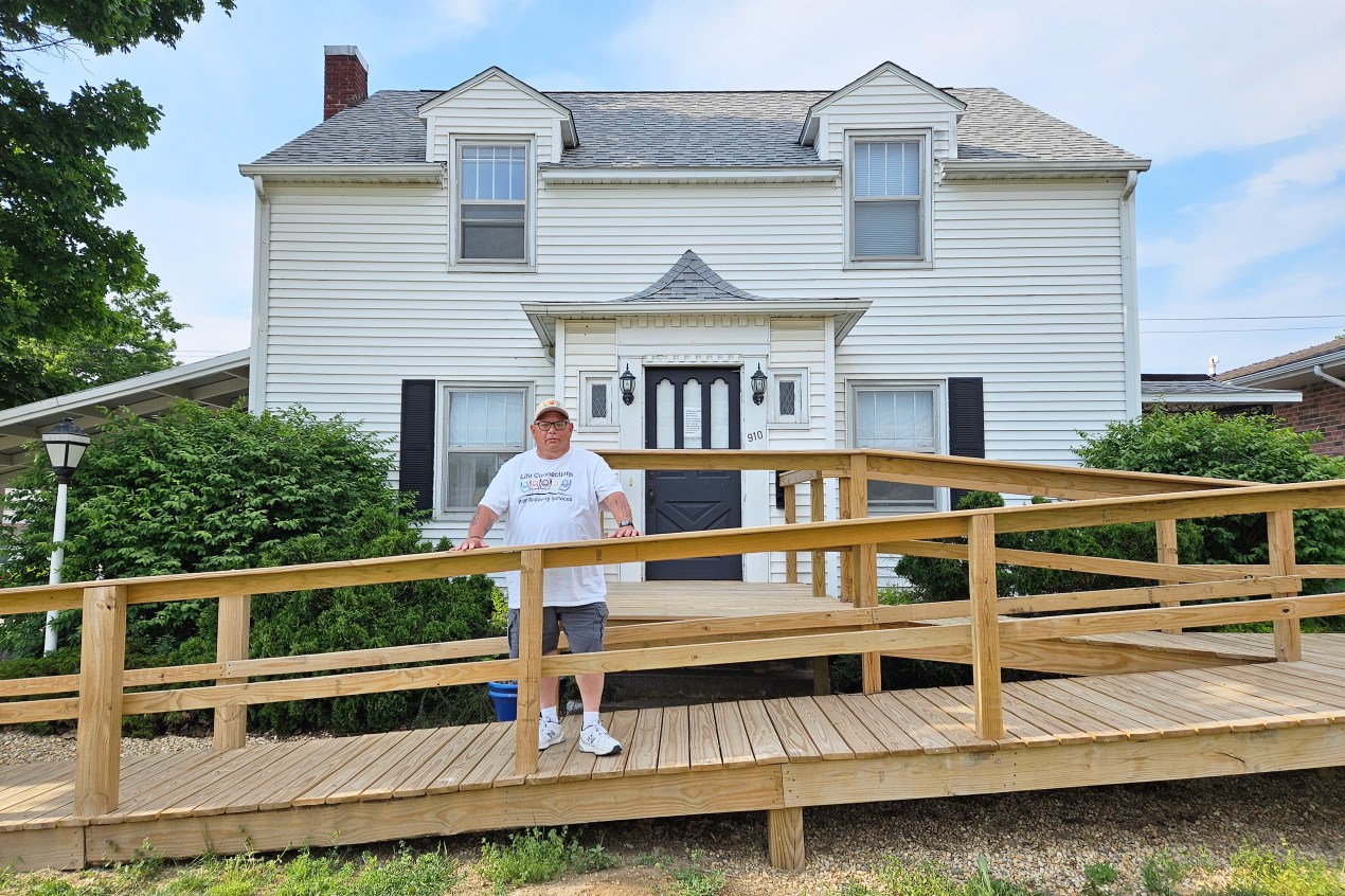 A photo of a man standing on a wooden deck outside of a respite home.