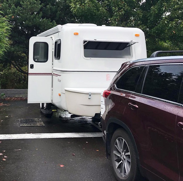 A photo of an RV trailer parked in a hospital parking lot.